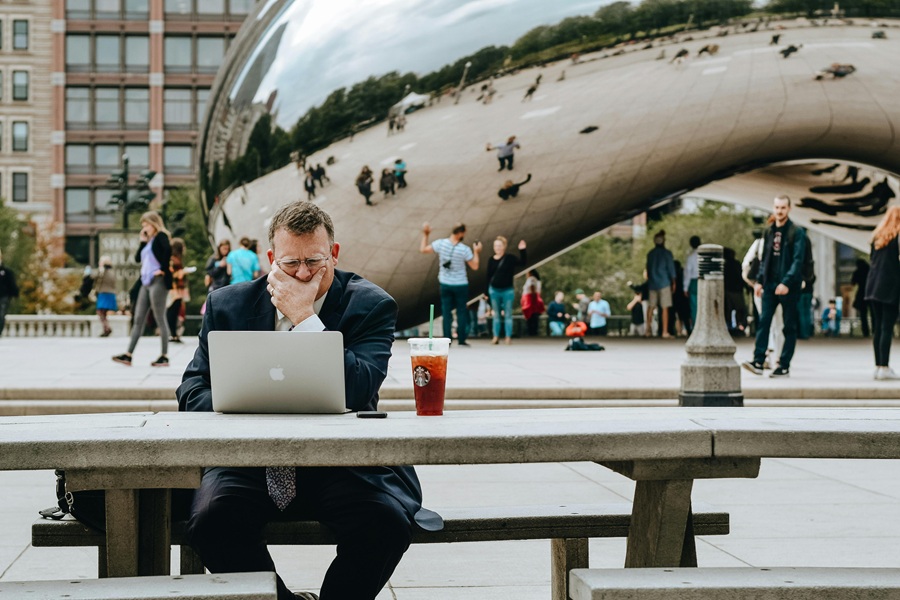Starbucks Secret Menu Refreshers Drink Recipes a Man Sitting Outside at a Picnic Table Drinking a Starbucks Drink working on a Laptop with the Chicago Bean in the Background