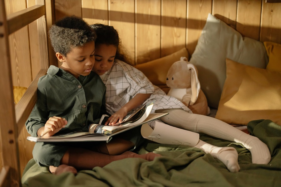 Funny Sibling Quotes for National Siblings Day a Brother and Sister Sitting Together on a Bed Reading a Book