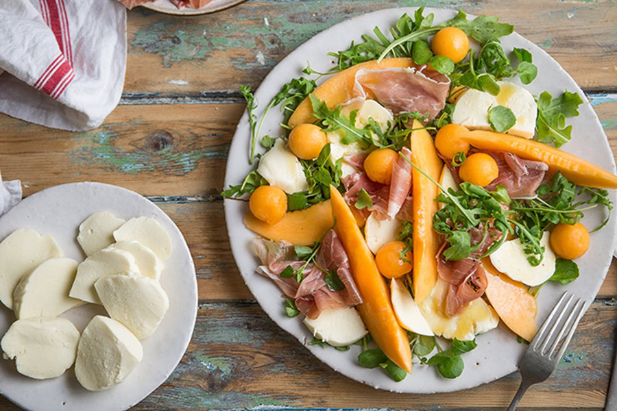 Brunch Recipes for Mother's Day a Plate of Melon, Mozzarella & Parma Ham Salad on a Wooden Surface