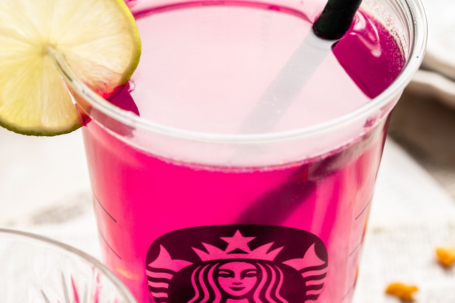 Starbucks Mango Dragon Fruit Refresher Copycat Recipe Close Up of a Starbucks Cup with Refresher Inside and a Lemon Wedge Garnishing the Cup