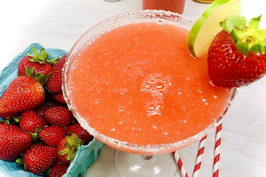 Large Batch Cocktails Close Up of a Strawberry Margarita Garnished with Strawberries and Limes