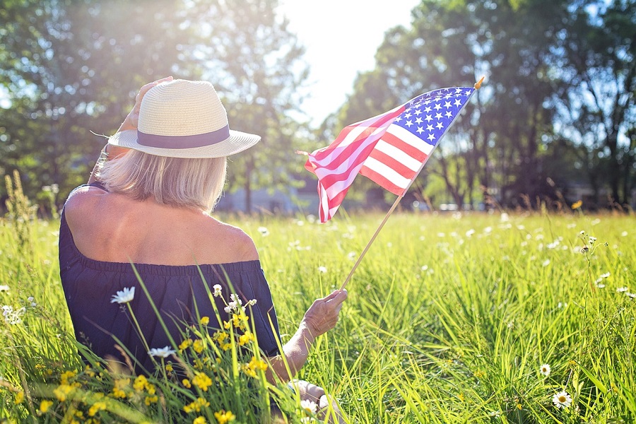 DIY 4th Of July Wreaths a Woman Sitting in a Field During a Sunny Day Holding a Small American Flag
