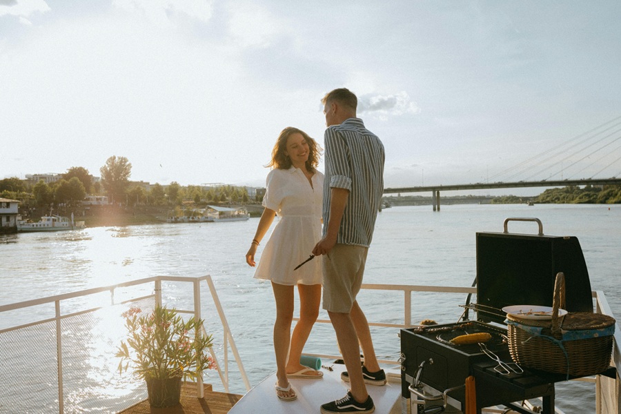 Summer Dinner Party Tips a Couple Standing on a Dock with a Grill Behind Them and a Table Set for Dinner