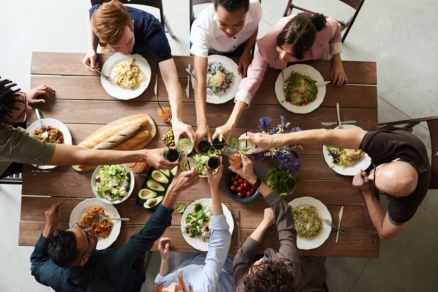 Summer Dinner Party Tips Overhead View of People Making a Toast at a Dinner Party