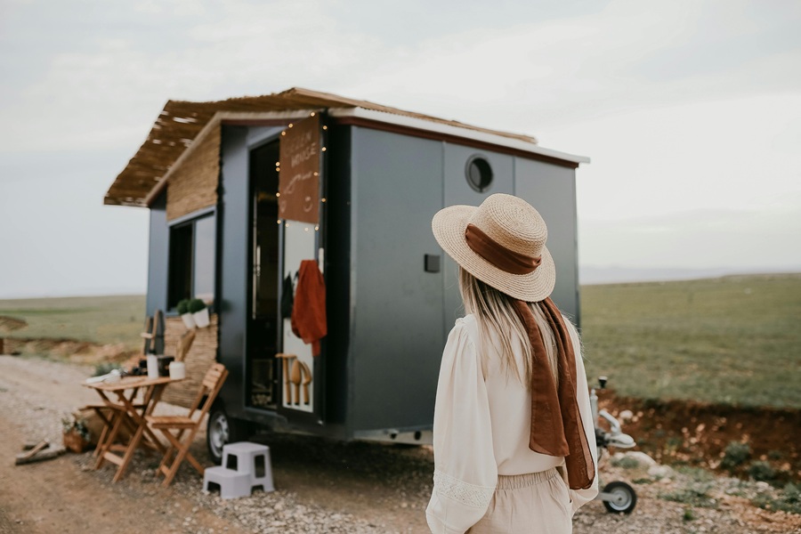 Small Camper Interior Ideas for Travelers a Woman Walking Toward a Tiny Home Camper with Bamboo Decor and a Bohemian Vibe