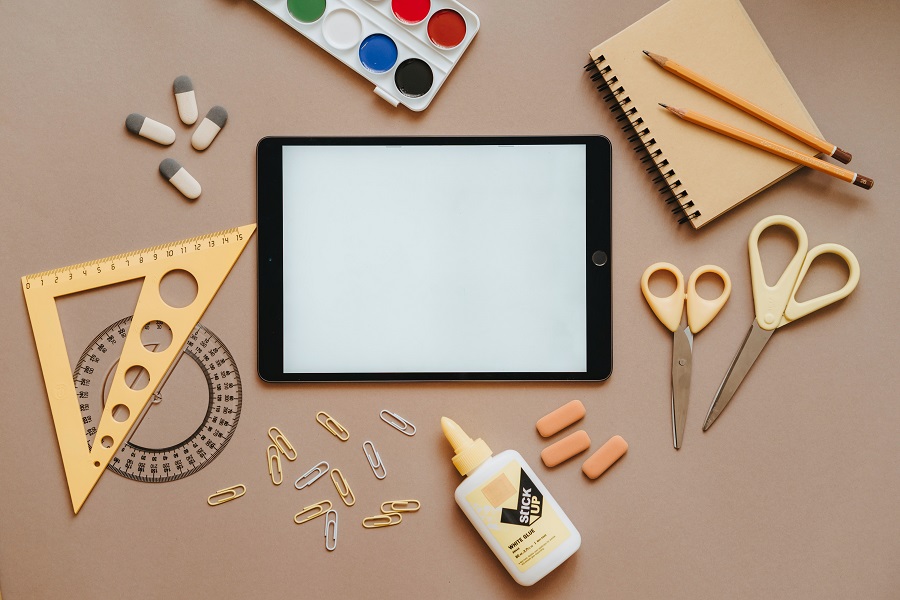 Best Back to School Party Ideas Overhead of a Tablet Surrounded by School Supplies on a Wooden Surface