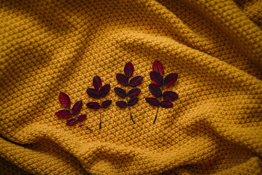 DIY Fall Decor Ideas Overhead View of Four Fall Leaves on a Deep Yellow Blanket