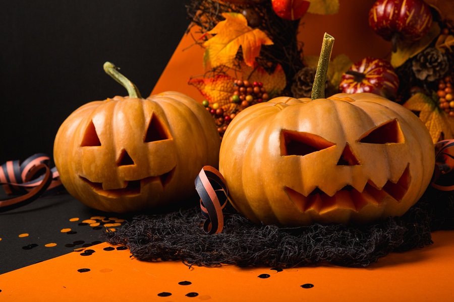 Halloween Fireplace Mantel Decor Ideas Two Jack-O-Lanterns Sitting on a Black Surface with Fall Foliage Behind Them