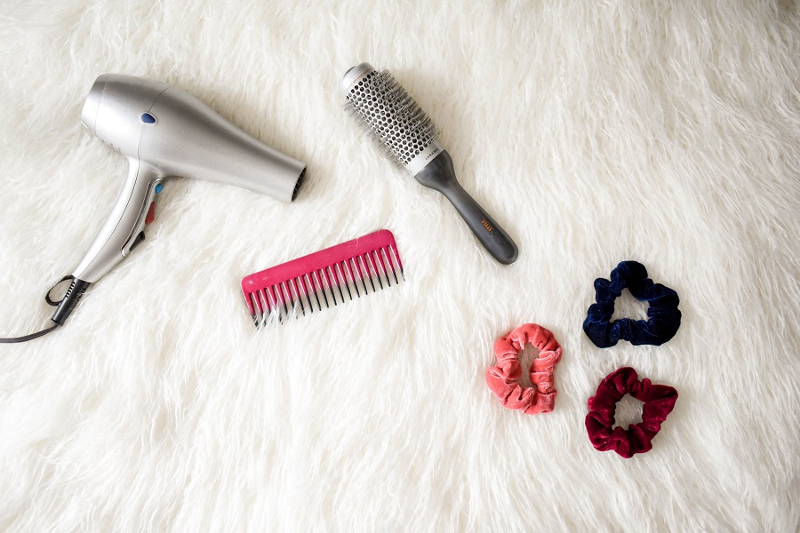 Easy Back to School Hairstyles a Brush, Comb, Hair Dryer, and Some Hair Ties on a White Furry Surface