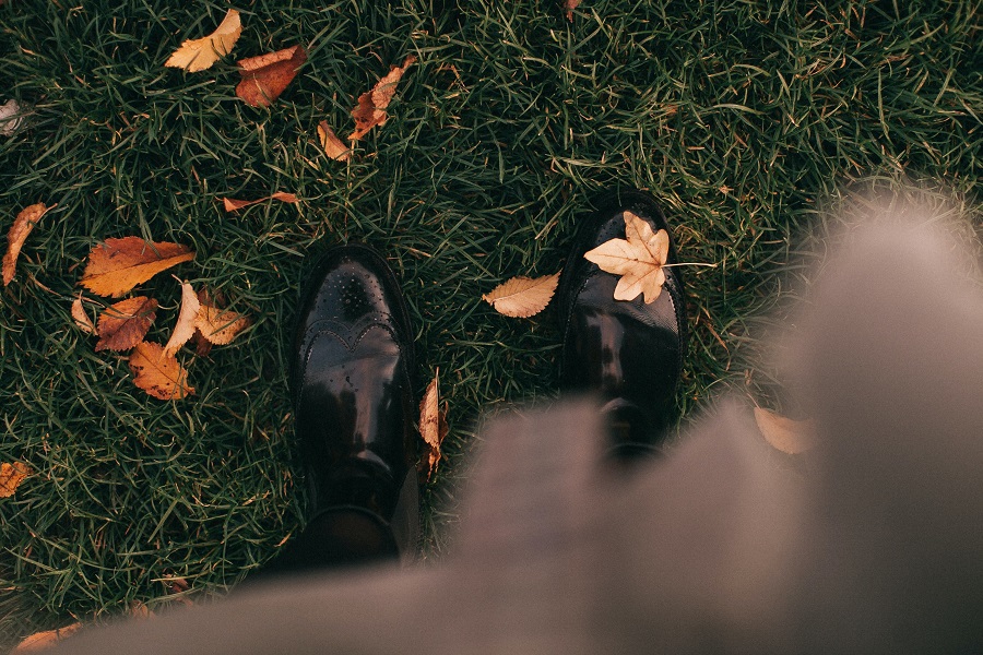 DIY Fall Decor Ideas View of a Woman's Shoes Standing on Grass with Fall Leaves Scattered Around