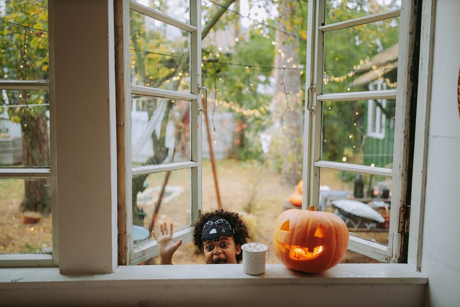 Halloween Fireplace Mantel Decor Ideas a Little Boy in a Halloween Costume Looking In Through a Window with a Jack-O-Lantern Sitting on the Window Sill