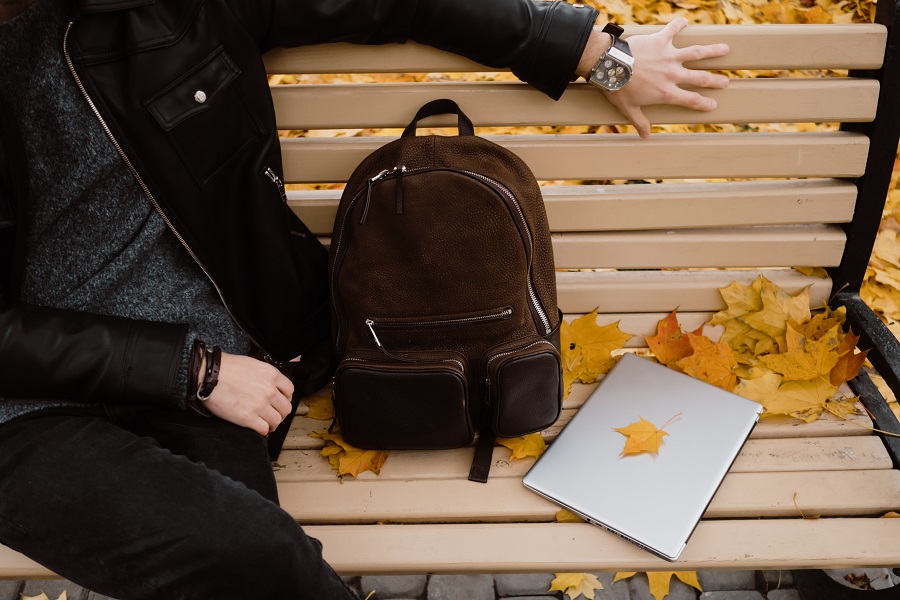 Fall Door Signs a Person Sitting on a Bench with a Backpack and a Laptop and Fall Leaves 