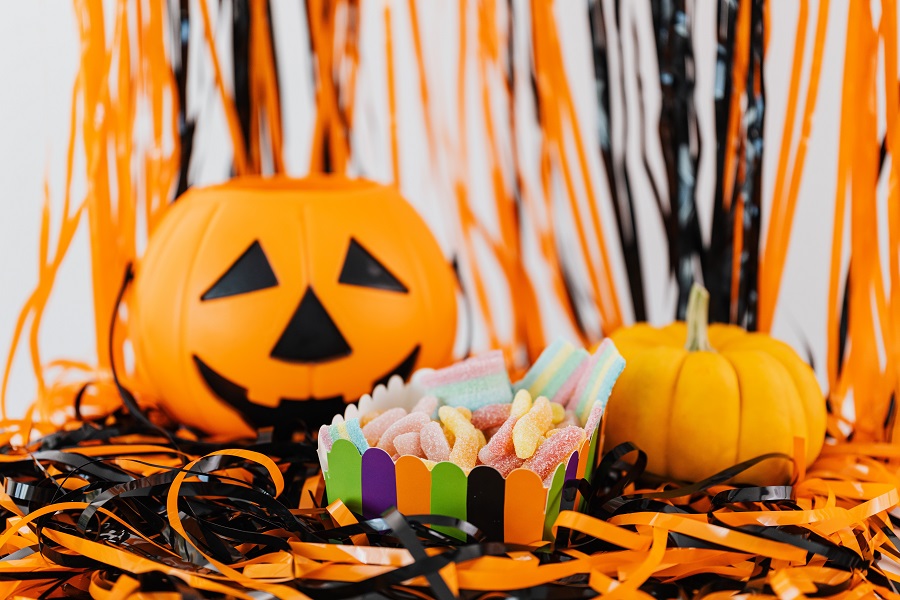 Candy Cocktail Recipes for Halloween a Jack-O-Lantern With Halloween Decor Behind It and a Bowl of Candy in Front