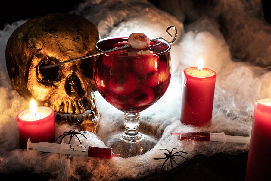 Halloween Jello Shots Recipes Close Up of a Giant Jello Shot with Eyeballs Inside Next to a Skull and Some Red Candles