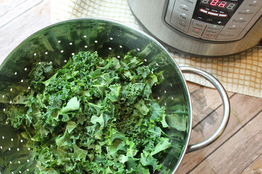 Creamy Kale Soup Recipe Overhead View of a Colander Filled with Kale Next to an Instant Pot 