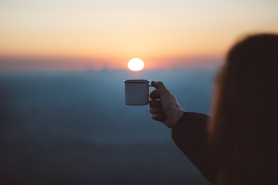 Jesus and Coffee Quotes a Person Holding Up a Cup of Coffee with the Sun Rising in the Background