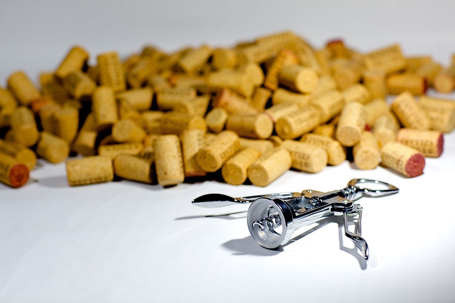 Best Coffee Wine Bar Ideas Close Up of a Corkscrew and a Pile of Corks on a White Surface