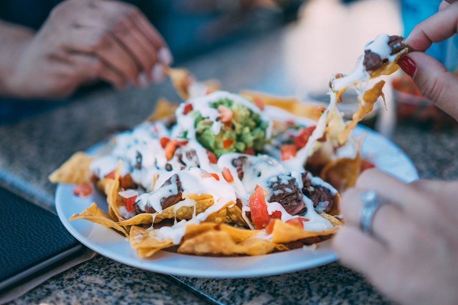 Best Power XL Vortex Air Fryer Recipes a Plate of Nachos with People's Hands Grabbing Chips