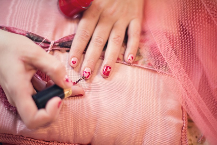Simple Wavy Nail Designs for Short Nails Close Up of a Person Painting Their Nails Red on a Pink Surface