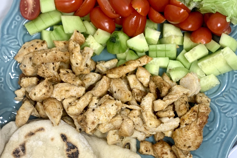 What to Serve with Tzatziki Dip a Platter of Chopped Chicken, Pita Bread, Cucumber, and Tomatoes