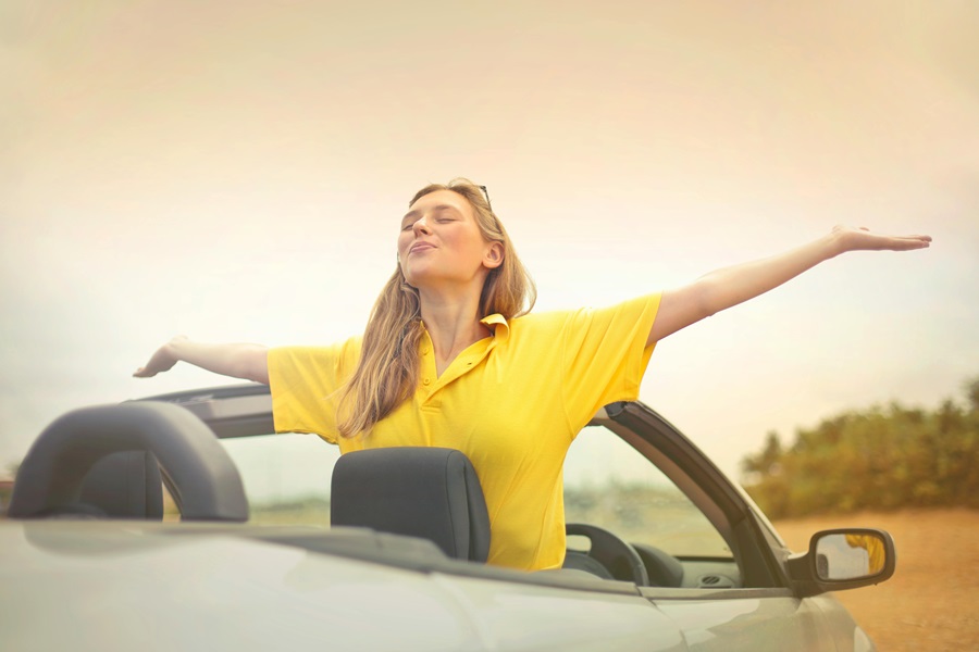New Cars Quotes for Car Enthusiasts a Woman Standing in a Car with Her Arms Spread Wide and the Top of the Car Down