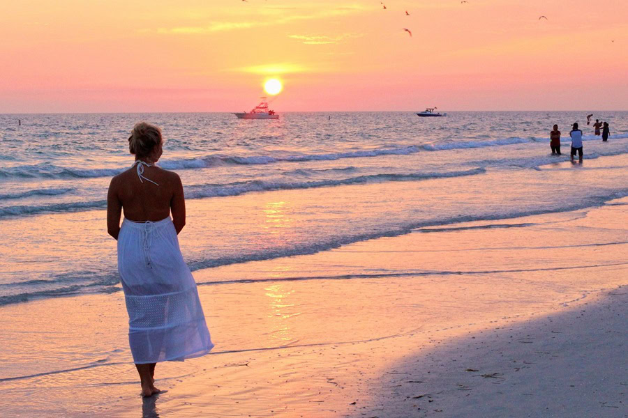 Summer Outfit Inspo Ideas a Woman Walking Along a Beach Wearing a Flowing Dress