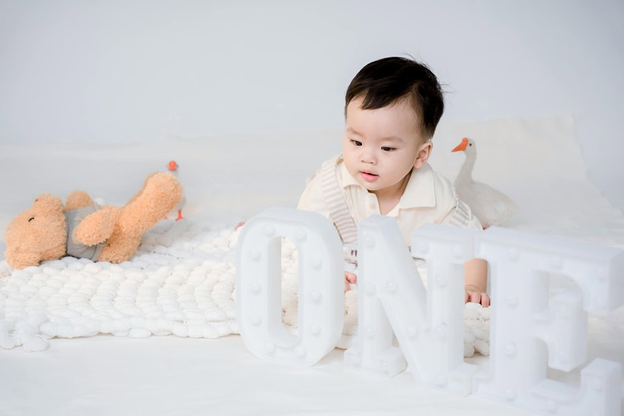 1st Birthday Party Ideas for Boys a Little Boy Laying On His Belly in a Photo Studio With a Small "ONE" Sign