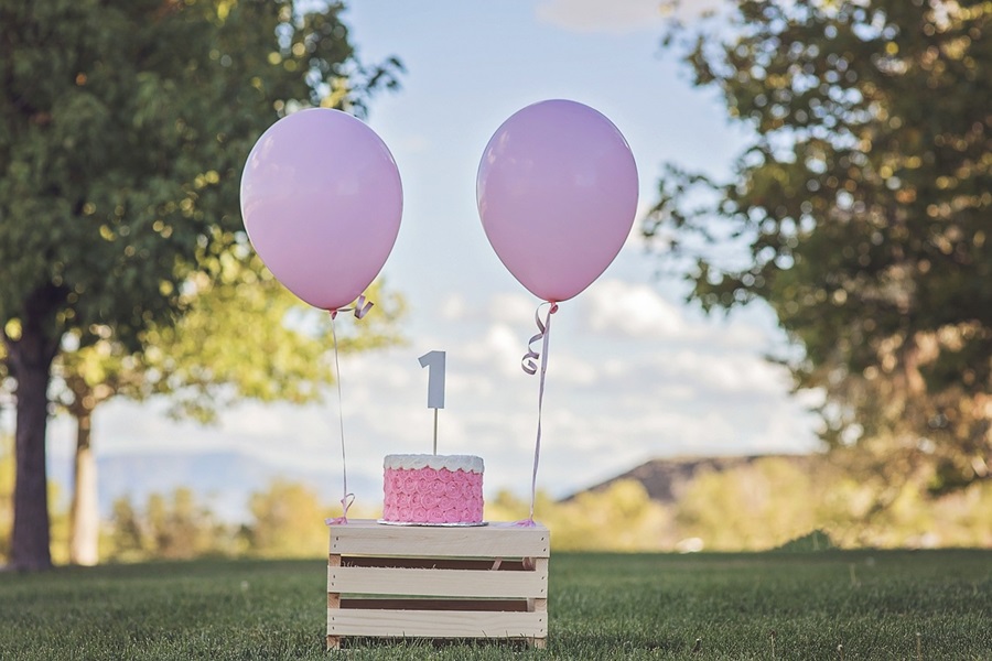 1st Birthday Party Ideas for Girls a Cake on a Stand with a "1" Candle and Two Pink Balloons