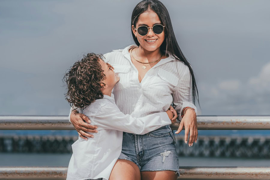 Women's Jort Outfit Ideas a Woman Wearing a White Button Up Shirt and Jorts Standing Outside Hugging Her Son