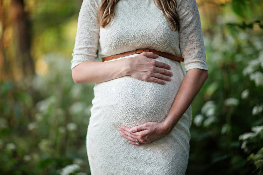 Inspiring Couple Maternity Quotes a Pregnant Woman Holding Her Belly in a Field of Flowers