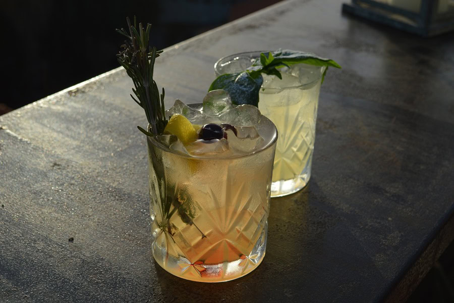 Big Batch Cocktails for Fall Two Cocktails with Thyme Sprigs on a Black Counter Top