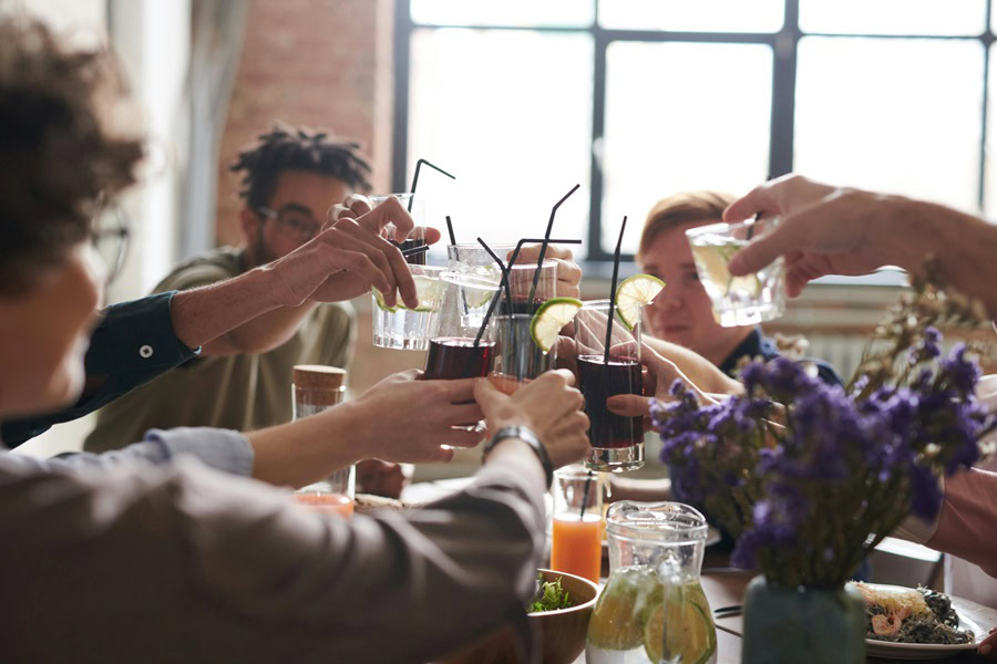 How to Batch Cocktails Friends Sitting Around a Table Toasting with Cocktails