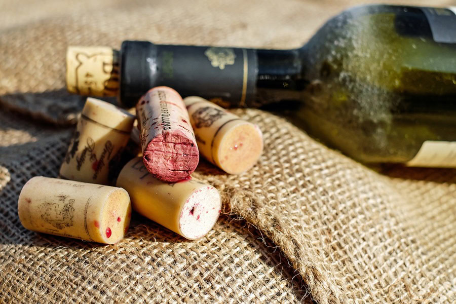 Easy DIY Wine Cork Ornament Close Up of Wine Corks in Front of an Empty Wine Bottle on Sand at a Beach