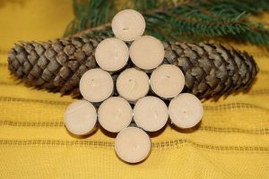 Easy DIY Wine Cork Ornament Close Up of a Wine Cork Ornament Resting on a Pine Cone with Pine Tree Branches in the Background