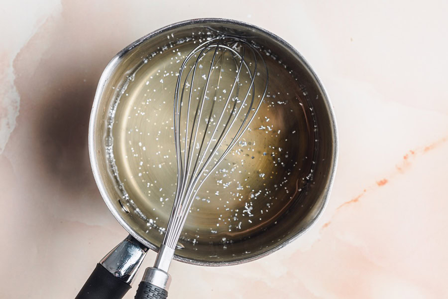 Champagne Jello Shots Recipe Silver Pot Filled with Clear Liquid and a Metal Whisk Inside