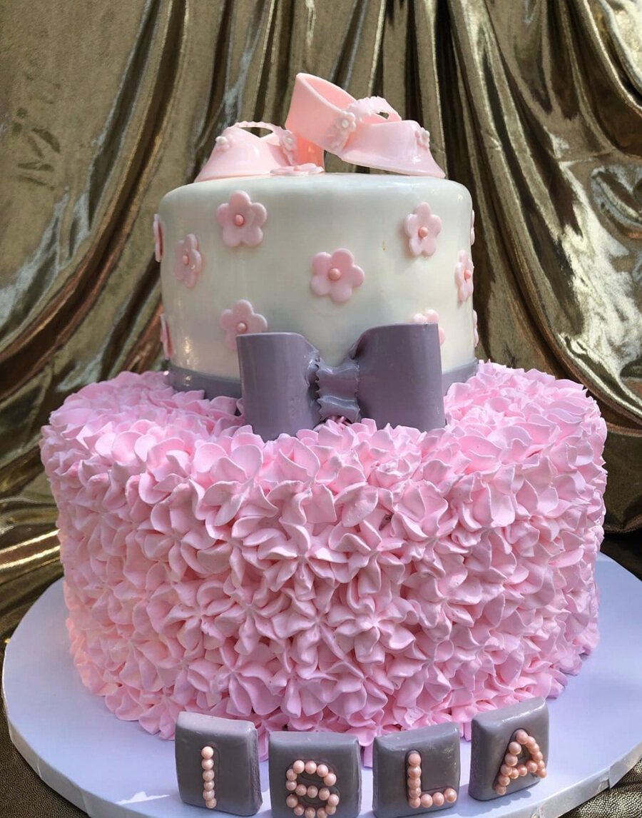 Baby Shower Cakes for Girls a Cake with Pink Whipped Cream Flowers on the Bottom Tier and a Purple Bow in the Middle