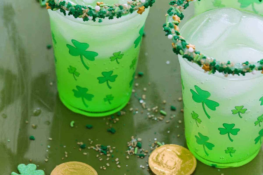 Green Cocktails for St Patricks Day Two Green Cocktails with Rainbow Sprinkles on the Rims and Gold Coins Around the Bases