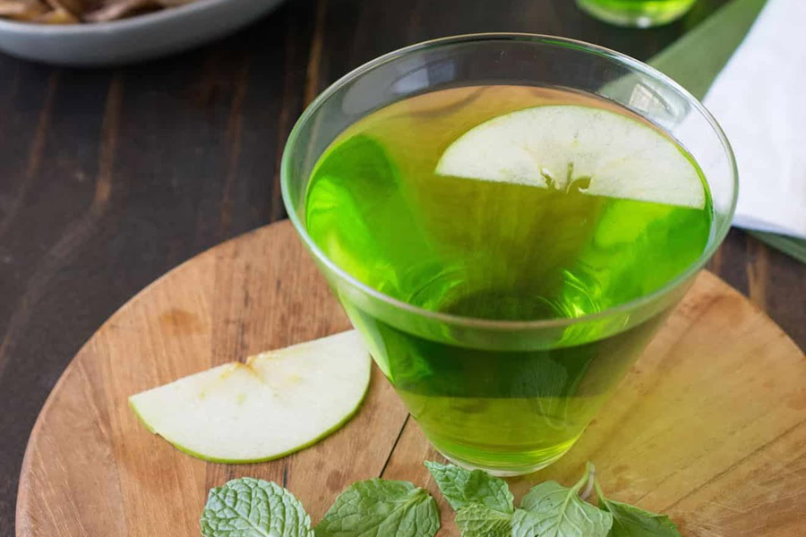 Green Cocktails for St Patricks Day a Green Cocktail Garnished with Thin Apple Slices on a Wooden Surface