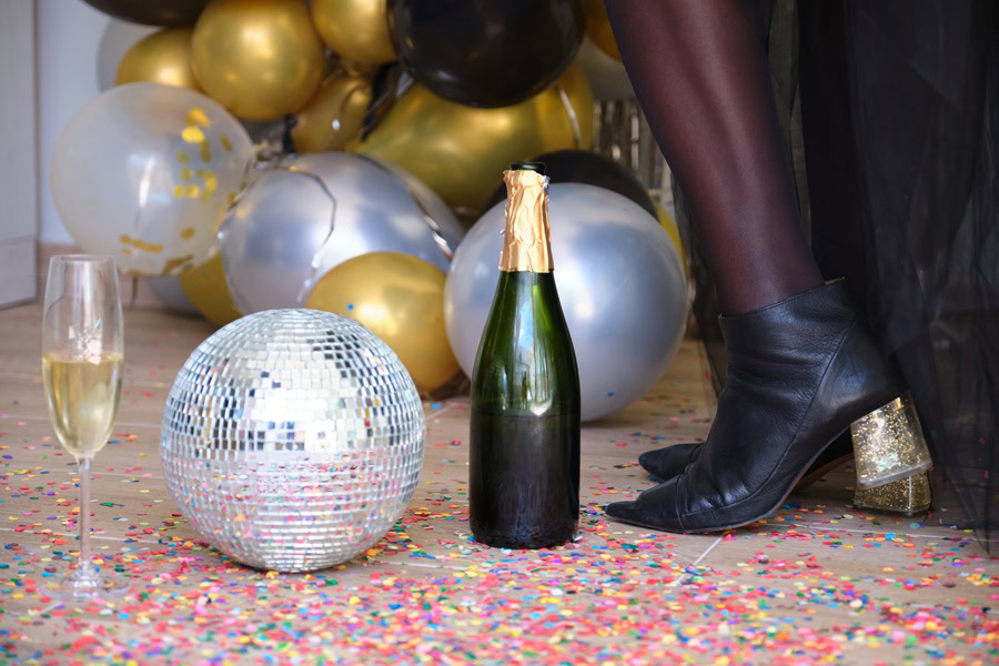 Pitcher Cocktails a Champagne Bottle Next to a Disco Ball on the Ground Next to a Person's Feet
