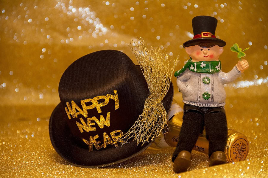 Pitcher Cocktails a Small Doll Standing Next to a Hat That Says Happy New Year