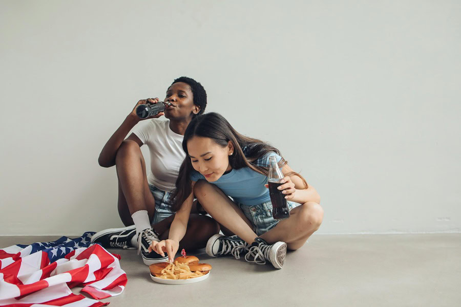 4th of July Cookies Two Women Sitting on a Ground Eating with an American Flag Next to Them