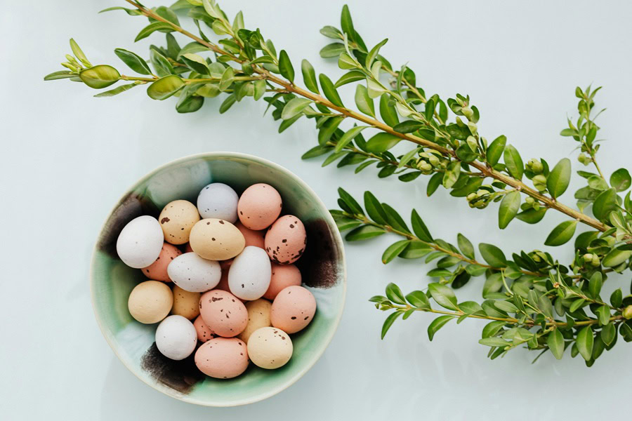 Christian Quotes for Easter Sunday a Bowl of Candy Eggs Next to a Branch with Leaves on a Table