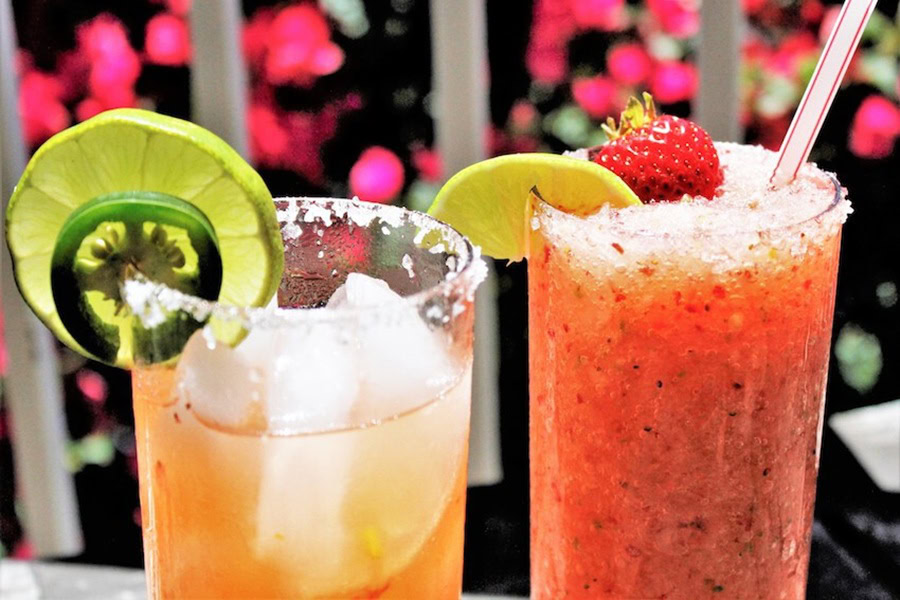Backyard BBQ Drinks for an Outdoor Party Strawberry Jalapeno Margarita Recipe on the Rocks in Two Glasses Garnished with Strawberries and Jalapenos