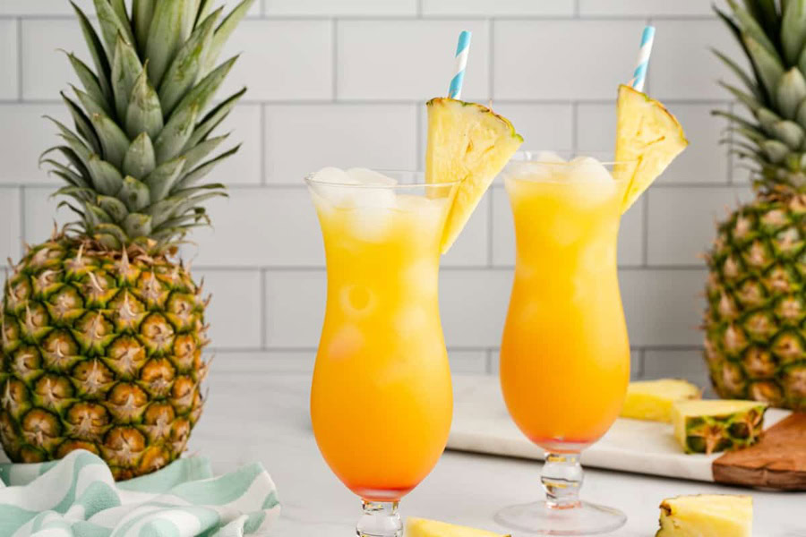 Backyard BBQ Drinks for an Outdoor Party Bahama Mama in Two Glasses Garnished with Pineapple and a Straw