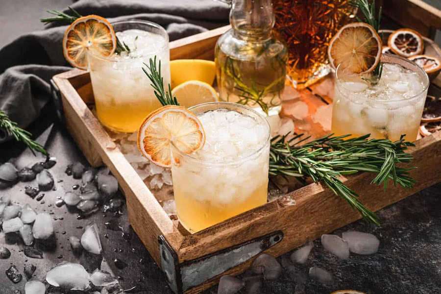 Backyard BBQ Drinks for an Outdoor Party Lemon Bourbon Cocktail with Rosemary in Two Glasses on a Serving Tray with Ingredients