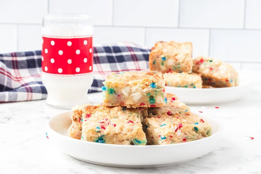 Red White and Blue Desserts 4th of July Gooey Butter Bars on a White Plate with a Red Cup in the Background