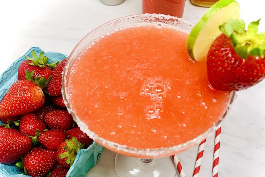 Red White and Blue Drink Recipes with Alcohol a Fresh Strawberry Margarita Garnished with a Strawberry Next to a Small Basket of Strawberries