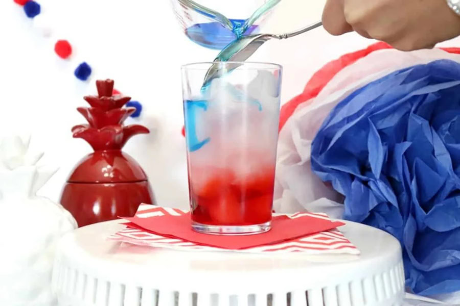 Red White and Blue Drink Recipes with Alcohol A Person Pourin Blue Liquid On an Upside Down Spoon Over a Glass Filled with White and Red Liquid