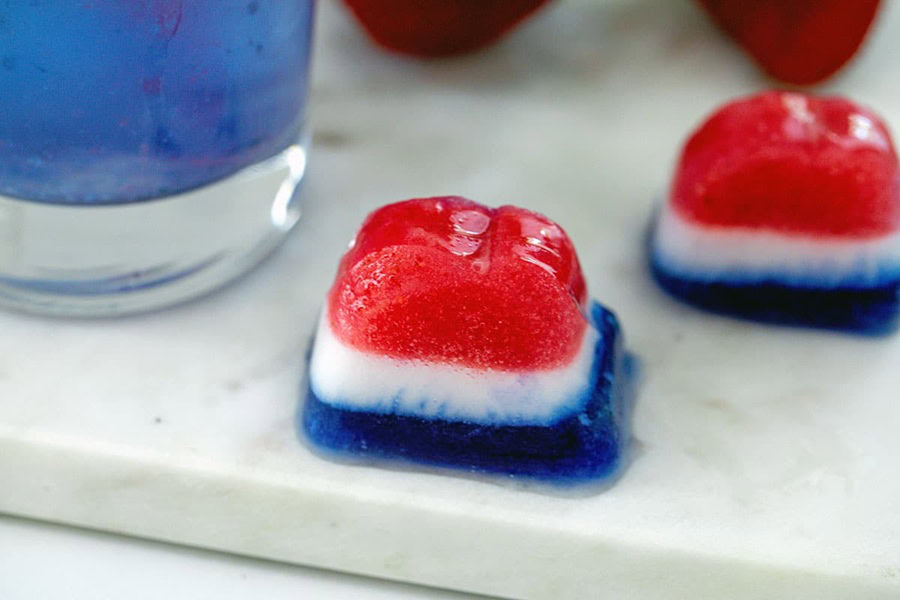 Red White and Blue Drinks Red, White, and Blue Ice Cubes on a Counter Top Next to a Drinking Glass