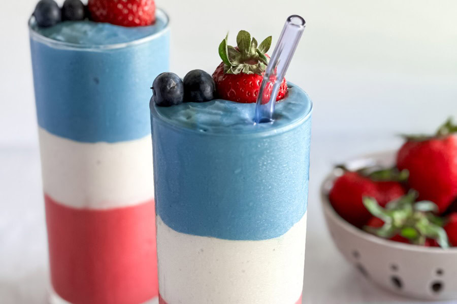 Red White and Blue Drinks Red, White, and Blue Smoothie in Tall Glasses with Blueberries and Strawberries